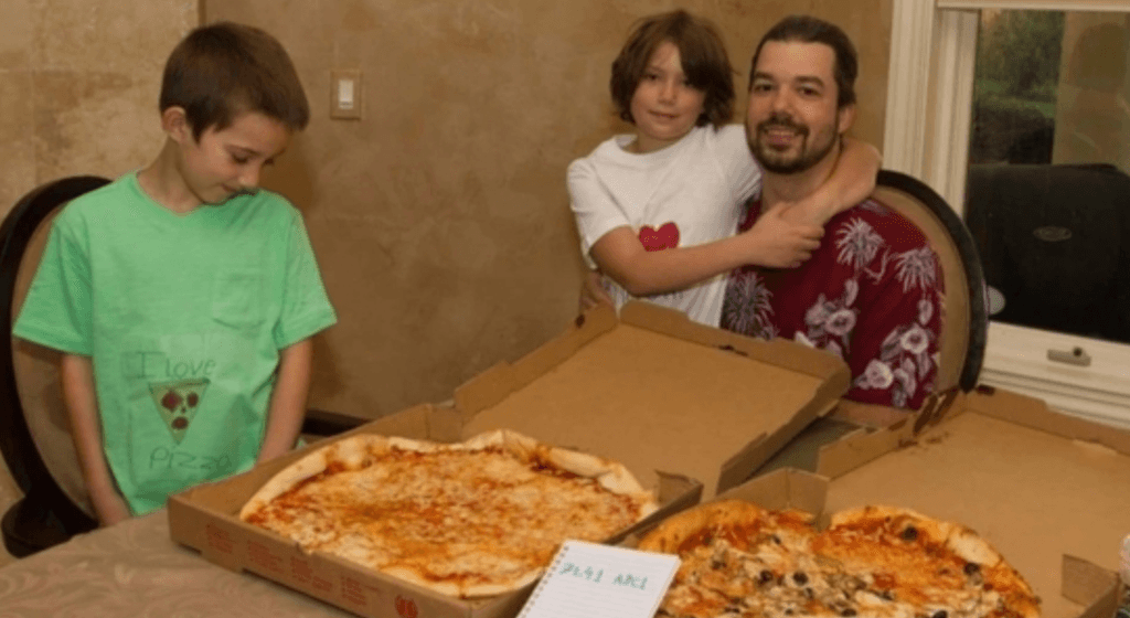 Laszlo Hanyecz en famille avec deux grandes pizzas, recréant la scène historique du premier achat de pizzas en Bitcoin